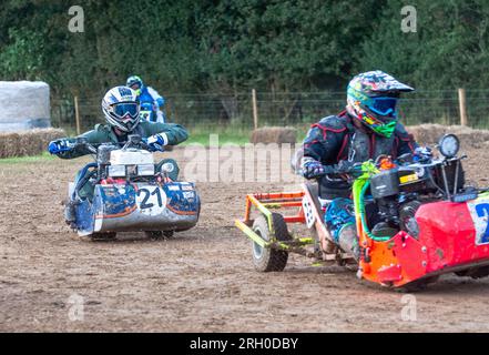 I piloti di rasaerba da corsa si lanciano per la posizione nella BLMRA 500, una corsa notturna di 500 km in stile le Mans in un campo nel West Sussex, Regno Unito. La British Lawn Mower Racing Association organizza il suo 50° anniversario di 12 ore di gara durante la notte sabato/domenica con 52 squadre, ognuna con tre piloti. Foto Stock