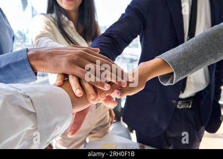 Team aziendali eterogenei che uniscono le mani in stack in ufficio, primo piano. Foto Stock