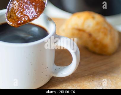 I grani di zucchero di canna aspirano il caffè caldo, fino a ottenere una consistenza sciroppata, prima di essere mescolati in un espresso nero appena fatto, pronto da bere, caldo Foto Stock