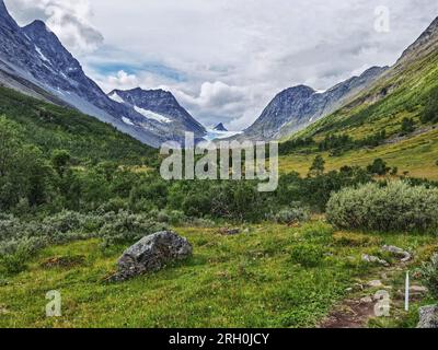 Oteren, Contea di Troms, Norvegia. 12 agosto 2023. Vista dall'escursione attraverso la valle del fiume glaciale da e verso la cima del ghiacciaio Steindal (Steindalsbreen) deflusso nella Norvegia artica. Lo Steindal Glacier è una destinazione popolare per gli escursionisti ambiziosi, nonché per coloro che vogliono assistere a un'incredibile riduzione. I cartelli eretti lungo la strada raccontano dove un tempo era il ghiaccio e negli ultimi anni, il deflusso ha perso molti metri di lunghezza e altezza. La regione di Tromso dovrebbe anche rompere ufficialmente le ''temperature più alte registrate'' il 12 agosto in caso di oltre 20c. (Immagine di credito: © sa Foto Stock