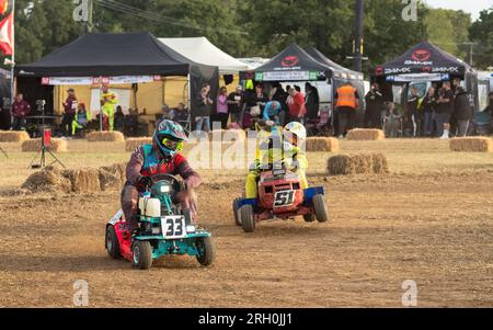 I conducenti di rasaerba da corsa si afferra per mantenere il controllo in curva con la BLMRA 500, una corsa notturna di 500 km in stile le Mans in un campo nel West Sussex, Regno Unito. La British Lawn Mower Racing Association organizza il suo 50° anniversario di 12 ore di gara durante la notte sabato/domenica con 52 squadre, ognuna con tre piloti. Viaggia a tutta velocità con il BLMRA 500, una corsa di 500 km in stile le Mans nel West Sussex, Regno Unito. La British Lawn Mower Racing Association organizza il suo 50° anniversario di 12 ore di gara durante la notte sabato/domenica con 52 squadre, ognuna con tre piloti. Foto Stock