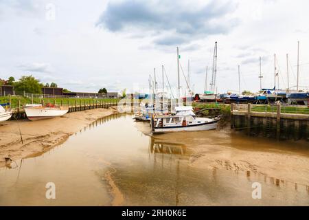 Le barche ormeggiavano sulle sponde fangose durante la bassa marea sul fiume Rother a Rye Harbour, un piccolo villaggio costiero vicino a Rye Town nell'East Sussex Foto Stock