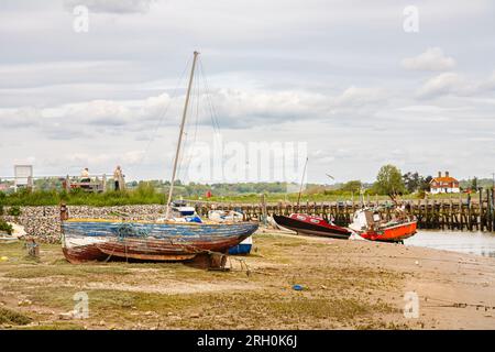Piccole barche si arenarono con la bassa marea sulle rive del fiume Rother, ormeggiate a Rye Harbour, un piccolo villaggio vicino alla città di Rye vicino alla costa nell'East Sussex Foto Stock