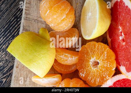 diversi tipi di agrumi in tavola, pompelmo rosso, mandarini arancioni e limone giallo in tavola Foto Stock