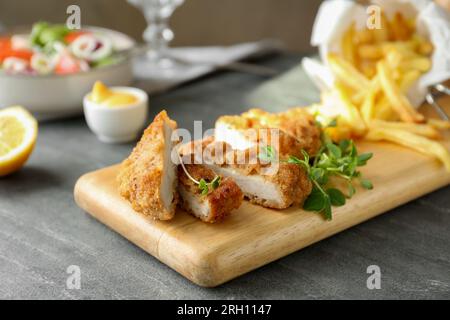 Deliziosa schnitzel tagliata servita con microgreen su un tavolo grigio Foto Stock