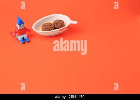 Slynchev Bryag, Bulgaria - 25 maggio 2023: Metà dell'uovo Kinder Joy con caramelle dolci e giocattolo su sfondo arancione, spazio per il testo Foto Stock