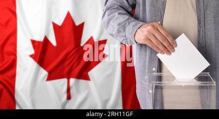 Uomo che mette il suo voto nelle urne contro la bandiera nazionale del Canada, primo piano. Design banner con spazio per il testo Foto Stock