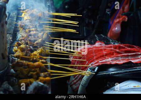 La scena di Sate Padang, un tipo di piatto indonesiano a base di carne spiedata e grigliata, cucinato a fiamma aperta in una bancarella di cibo di strada. Foto Stock