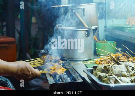 La scena di Sate Padang, un tipo di piatto indonesiano a base di carne spiedata e grigliata, cucinato a fiamma aperta in una bancarella di cibo di strada. Foto Stock