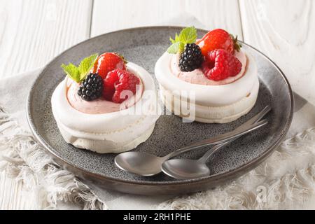 Dolci Pavlova gourmet con frutti di bosco freschi, panna e menta da vicino in un piatto sul tavolo. Orizzontale Foto Stock