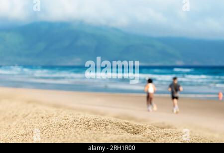 Uomini e donne che corrono su una spiaggia tropicale al tramonto. Due corridori sulla spiaggia, silhouette di persone che fanno jogging. Foto Stock