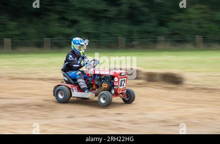 Un pilota di rasaerba da corsa corre all'alba con la BLMRA 500, una corsa notturna di 500 km in stile le Mans in un campo nel West Sussex, Regno Unito. La British Lawn Mower Racing Association organizza il suo 50° anniversario di gara di 12 ore durante la notte sabato/domenica con 52 squadre, ciascuna con un massimo di tre piloti. Foto Stock