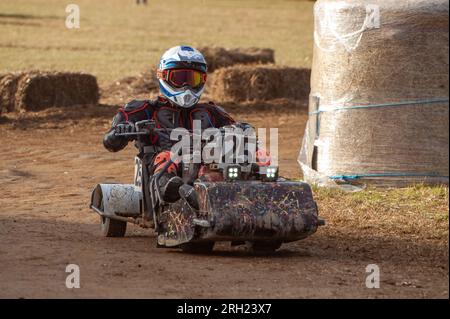 Billingshurst, West Sussex, Regno Unito. 12 agosto 2023. Un pilota di rasaerba da corsa prende una curva sul circuito all'alba con la BLMRA 500, una gara notturna di le Mans di 500 km in un campo nel West Sussex, Regno Unito. La British Lawn Mower Racing Association organizza il suo 50° anniversario di gara di 12 ore durante la notte sabato/domenica con 52 squadre, ciascuna con un massimo di tre piloti. Crediti: Andy Soloman/Alamy Live News Foto Stock