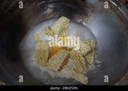 Prepara i noodles indonesiani istantanei in una grande padella con le uova nella città di Medan, Indonesia. Fotografia di Street food. Foto Stock