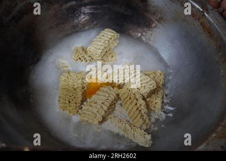 Prepara i noodles indonesiani istantanei in una grande padella con le uova nella città di Medan, Indonesia. Fotografia di Street food. Foto Stock