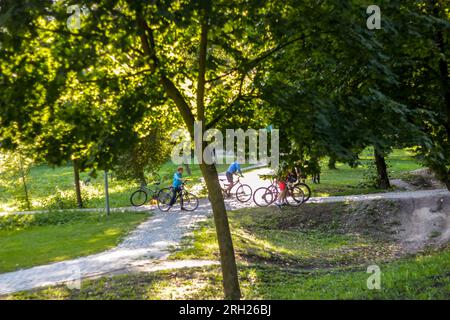 Primo piano per bambini in bicicletta su un parco con pista a pompa alla luce del tramonto. Pista ciclabile asfaltata, parco giochi per bambini. Concetto di sport per adolescenti, bulli Foto Stock