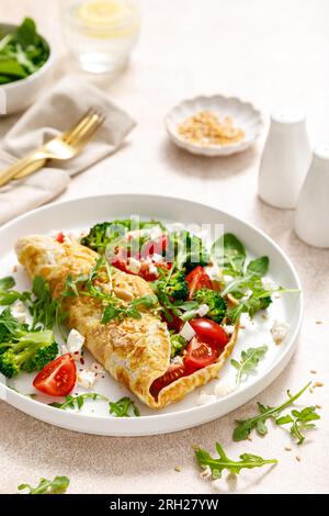 Omelette ripiene di pomodoro, broccoli feta e insalata verde fresca. Cibo salutare per la colazione Foto Stock