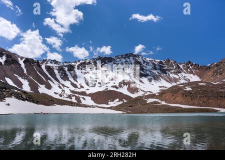 Superficie d'acqua di un lago morenico ai piedi della montagna. Ora legale. Cambiamento climatico Foto Stock