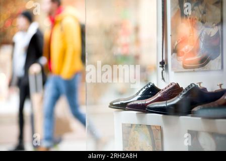 Scarpe da uomo in un negozio contro le persone che camminano per strada Foto Stock