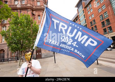 Manchester, Regno Unito. 12 agosto 2023. Pro Trump 2024 sostenitore di fronte a una folla di 80 persone che si sono presentate il 12 agosto 2023 per celebrare il massacro di Peterloo del 16 agosto 1819 che ha avuto luogo a Manchester. Gli organizzatori hanno incolpato un evento rivale "Peterloo March for Democracy", organizzato per il 19 agosto 2023, oltre ad altre proteste ed eventi, tra cui il carnevale caraibico di Manchester, una protesta Trans Right e una protesta iraniana per il cambiamento proregime in piazza St Peters a Manchester. La piccola folla marciò verso il monumento al massacro di Peterloo nel centro di Manchester. Alla presenza c'era il chan climatico Foto Stock