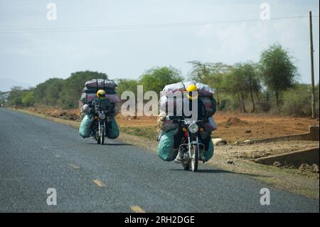 Due motociclisti boda boda che trasportano sacchi di carbone sul retro delle loro moto, Nakuru, Kenya, Africa orientale Foto Stock