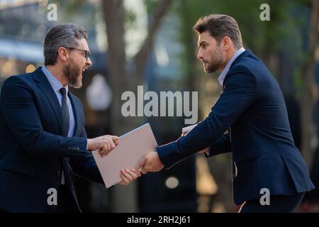 Concorrenza aziendale, leadership. Uomini d'affari che lottano all'aperto. Lavoratori d'ufficio arrabbiati in città. Uomini e partner in disaccordo. Concorrenza commerciale. Affari Foto Stock