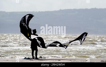 Gli amanti del kite surf apprezzano il clima ventoso di Camber Sands, nell'East Sussex. Secondo il Met Office, le temperature potrebbero raggiungere i 30 °C in alcune parti del Regno Unito la prossima settimana, dopo che le forti piogge bagnano il paese. Data foto: Domenica 13 agosto 2023. Foto Stock