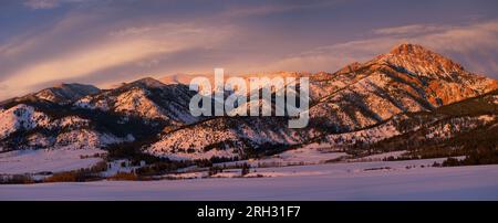 Piccole fattorie e campi ricoperti di neve sotto Ross Peak (a destra) e la catena montuosa Bridger al tramonto in inverno. Bozeman, Montana, USA. Foto Stock