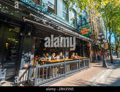 Persone che si godono un drink al sole in una giornata estiva a Gastown, Vancouver, Canada Foto Stock