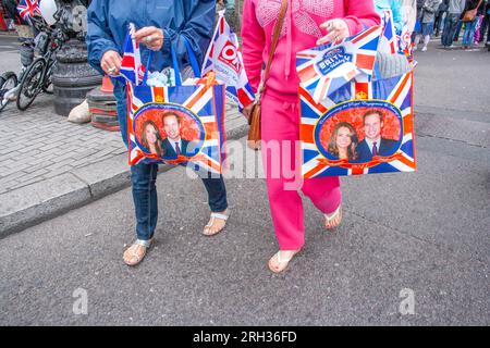 Due persone che camminano con borse con il ritratto di Caterina, duchessa di Cambridge, e suo marito il principe William, Londra, Regno Unito Foto Stock