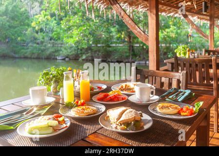 Tavolo per la colazione vicino al lago in un resort asiatico. Foto Stock