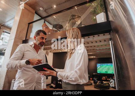 I leader aziendali discutono le statistiche finanziarie della loro azienda sul tablet durante la pausa in ufficio Foto Stock