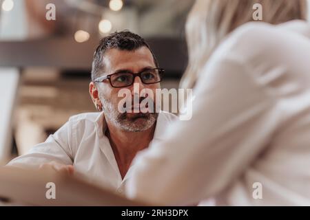 Una coppia d'affari ha una conversazione mentre si prende una pausa dal lavoro. Uomo d'affari di mezza età che ascolta attentamente la sua adorabile moglie, socio d'affari Foto Stock