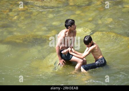 Doodhganga Yousmarg, Kashmir. Il 13 agosto, gli studenti del Kashmiri trovano sollievo dal caldo mentre si raffreddano nelle rinfrescanti acque di Doodhganga Yousmarg, trasformando una giornata soffocante in una fuga memorabile. Photos by Credit: Danish Showkat/Alamy Live News Foto Stock