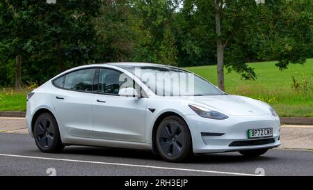 Milton Keynes, Regno Unito - 10 agosto 2023: 2023 auto elettrica Tesla Model 3 a lungo raggio awd bianca che guida su una strada di campagna inglese. Foto Stock