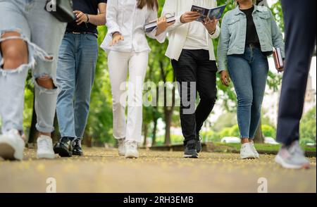 Foto parziale di studenti universitari che camminano su un marciapiede, che escono in città dopo le lezioni, foto con vista dall'alto. Foto Stock