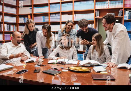 Due professori e i loro studenti ridono e si divertono in una biblioteca Foto Stock