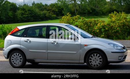 Milton Keynes, Regno Unito - 13 agosto 2023: 2003 auto Ford Focus argento che guida su una strada di campagna inglese. Foto Stock