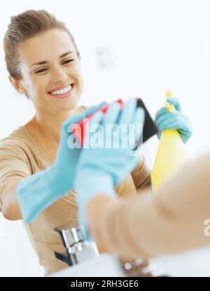 Felice giovane casalinga specchio di pulizia in bagno Foto Stock