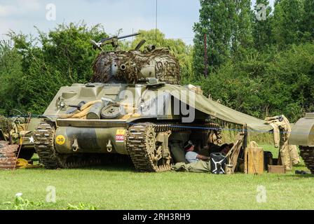 Rievocazione di un accampamento di carri armati Sherman della seconda guerra mondiale. Equipaggio di carri armati sotto la tela accanto all'armatura della seconda Guerra Mondiale in tempo di guerra Foto Stock