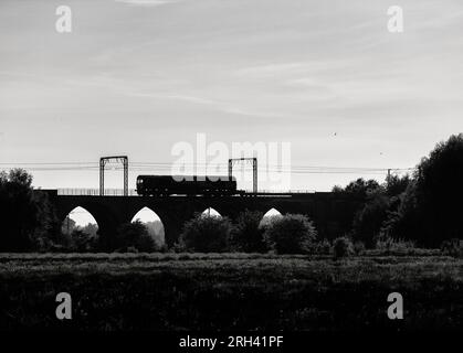 Sillhouette di una DB Cargo rail UK classe 66 locomotiva (66063) che attraversa il viadotto di Garnock Longford, a sud di Kilwinning, Ayrshire (fiume Garnock) Foto Stock
