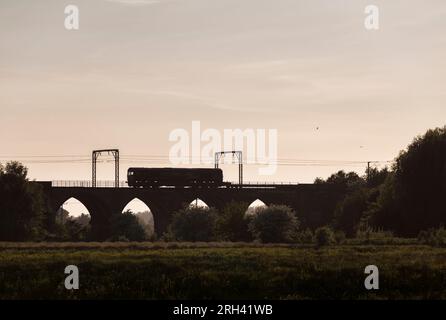 Sillhouette di una DB Cargo rail UK classe 66 locomotiva (66063) che attraversa il viadotto di Garnock Longford, a sud di Kilwinning, Ayrshire (fiume Garnock) Foto Stock