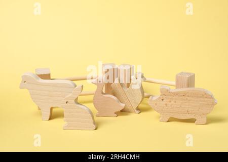 Animali di legno e recinzione su sfondo giallo. Giocattolo per bambini Foto Stock