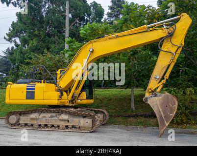 Attrezzature per costruzioni pesanti nel parcheggio. Escavatore benna. Auto pesante gialla. Attrezzature per l'edilizia. Senza lavoro. Senza un conducente Foto Stock