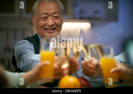 un anziano asiatico brindisi durante la riunione di famiglia felice e sorridente Foto Stock