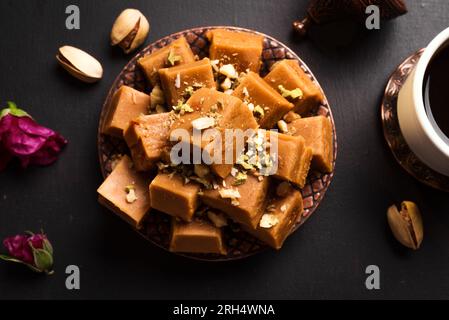 Sherbet al caramello con noci pistacche e caffè turco su sfondo nero, spazio copia. Tradizionale Iris o sherbet da dessert medio-orientale. Foto Stock