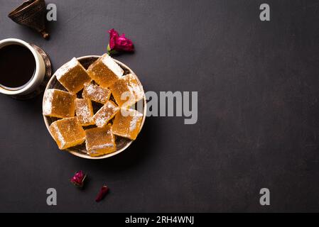 Rahat Locum Turkish Delight e caffè turco in tazza - dessert tradizionale su sfondo nero, spazio copia. Foto Stock