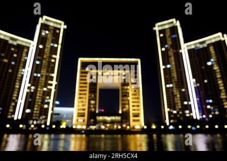 Città sfocate le luci di St Regis Hotel a Tianjin, Cina, paesaggio urbano circolare bokeh di notte sfondo astratto. Foto Stock