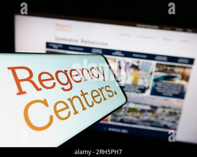 Smartphone con logo dell'azienda americana Regency Centers Corporation sullo schermo di fronte al sito Web aziendale. Concentrarsi sul centro del display del telefono. Foto Stock