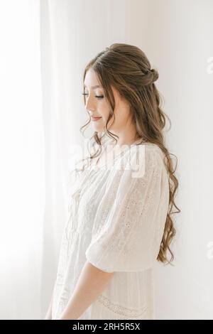 donna eterea ispanica in abito da sposa con capelli e trucco Foto Stock